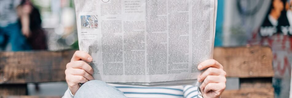 man sitting on bench reading newspaper